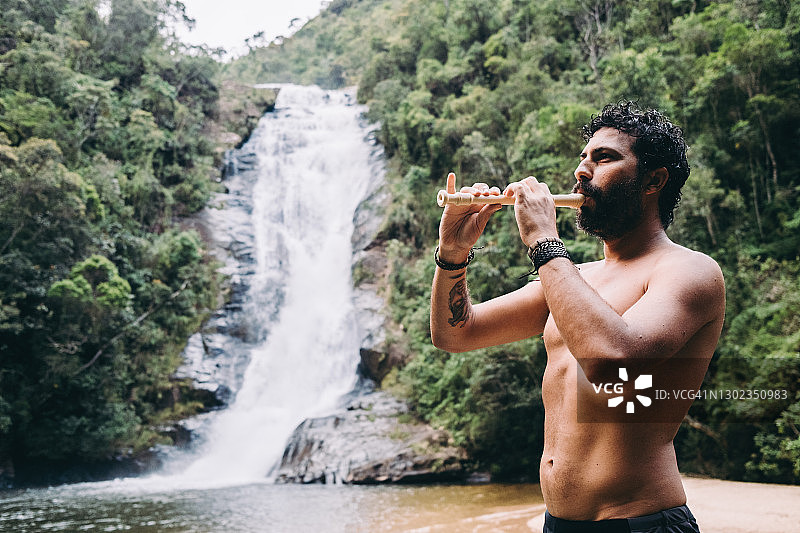 男人在瀑布旁吹长笛图片素材