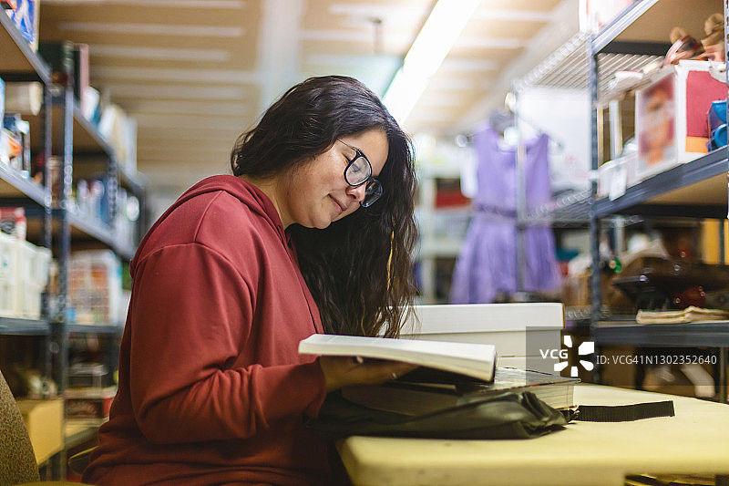 Z世代女大学生在仓库工作休息时学习摄影作品图片素材