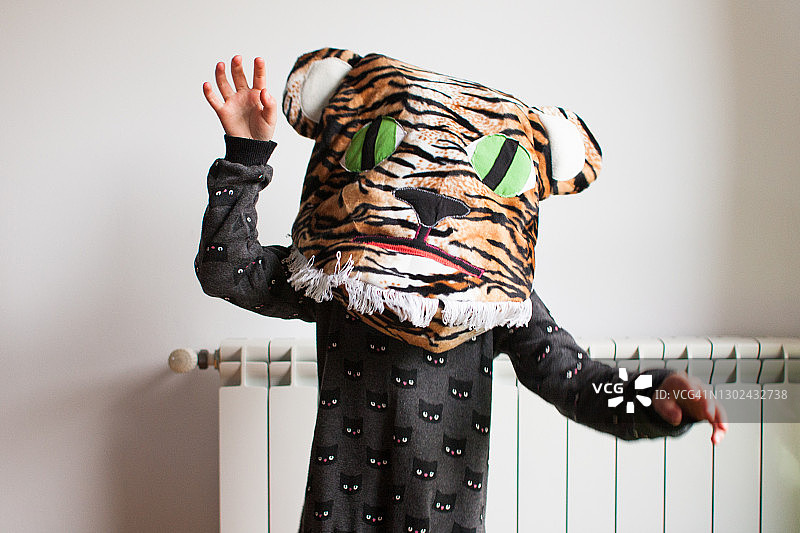 穿着黑猫裙子，抱着自制猫脸垫子的女孩在家玩耍图片素材