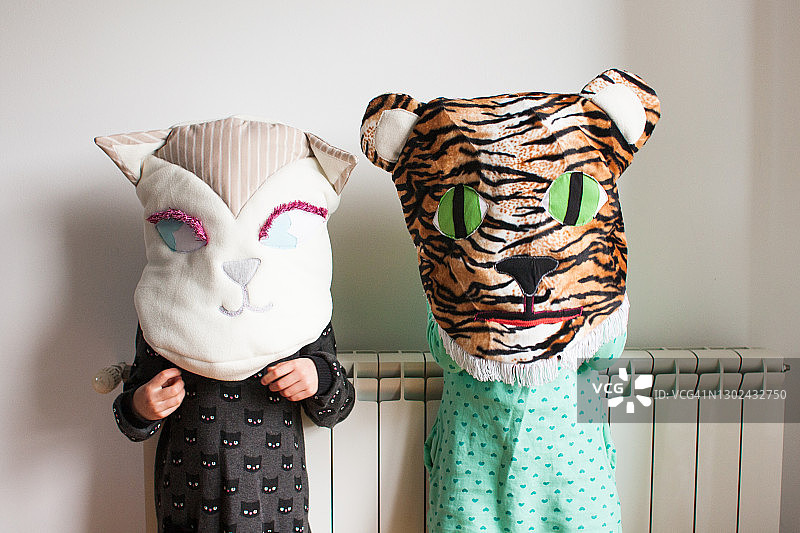 两个女孩在家里玩装扮游戏，手工制作猫和老虎脸垫图片素材