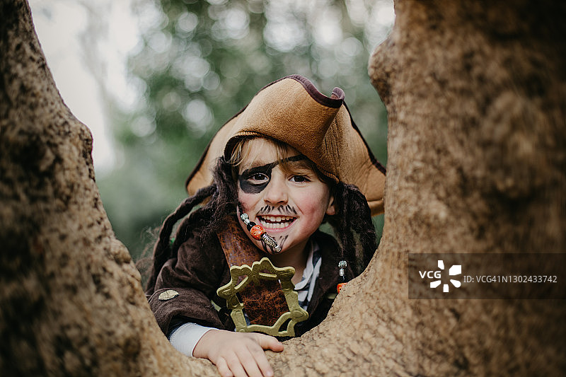 打扮成海盗躲在树后的男孩图片素材