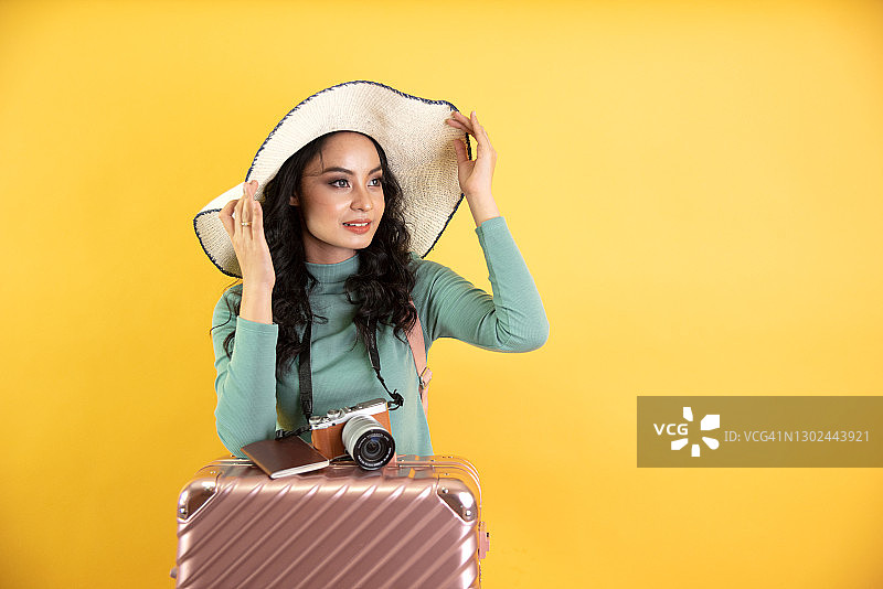 快乐的年轻亚裔女子手持帽子相机旅行包的肖像照片图片素材