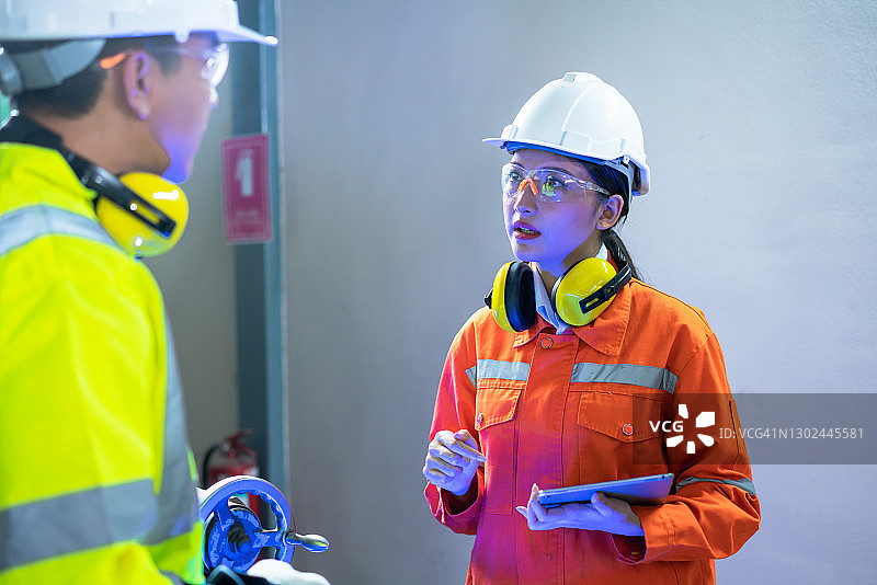 工厂里的年长工人在女工程师的指导下操作机器图片素材