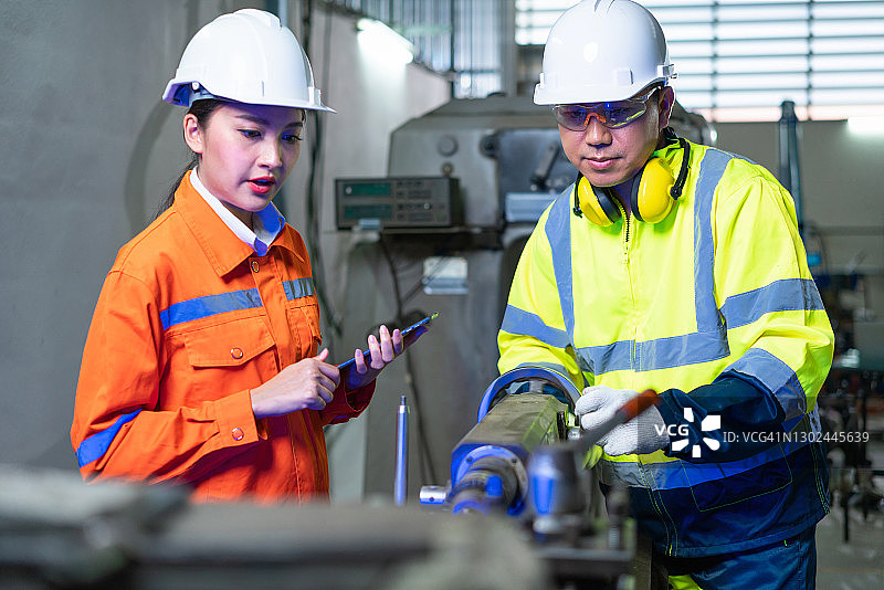 工厂里操作机器的年长工人和女工程师图片素材