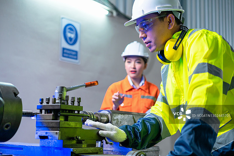 工厂里的年长工人和女工程师操作机器图片素材