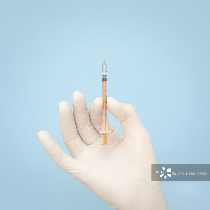 戴手套的手持注射器，准备接种新冠疫苗图片素材