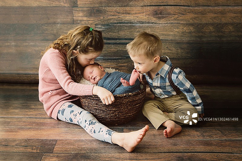 女孩和男孩亲吻新生弟弟图片素材