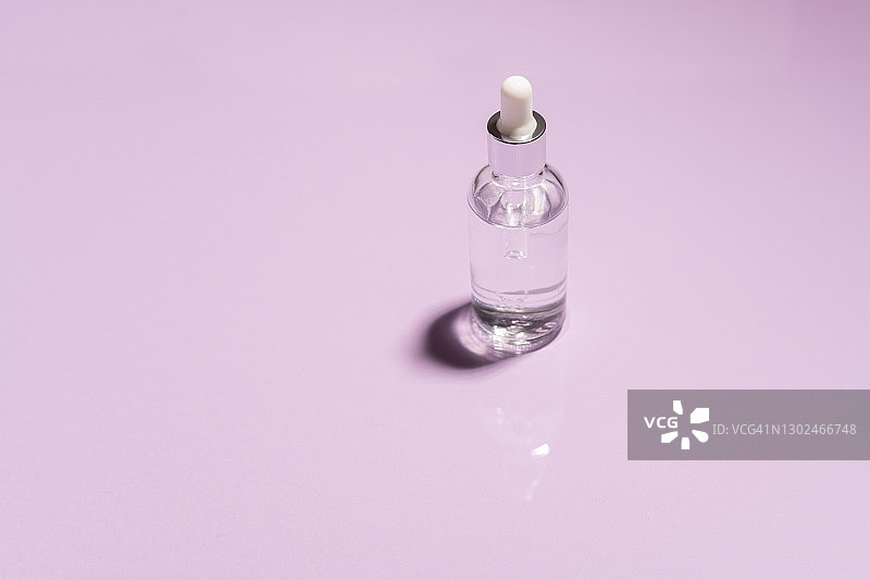 粉色背景上的透明质酸精华液玻璃罐图片素材