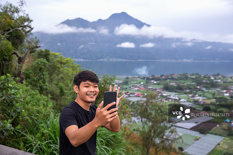在山顶进行视频通话的东南亚男人图片素材