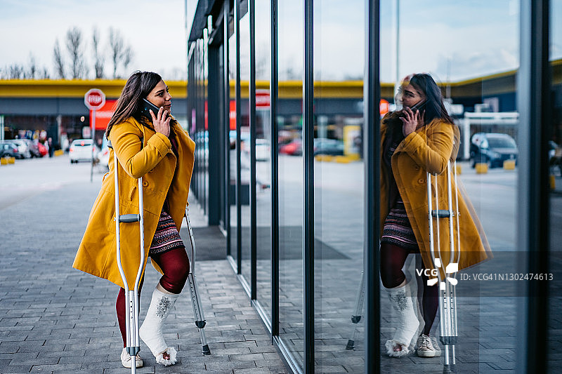 脚上打着石膏，正在打电话的女人图片素材