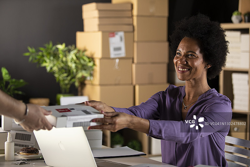 微笑的女商人向顾客递送包裹图片素材