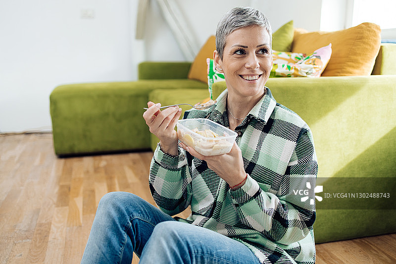 美丽的女人在塑料盒里吃粥的肖像图片素材