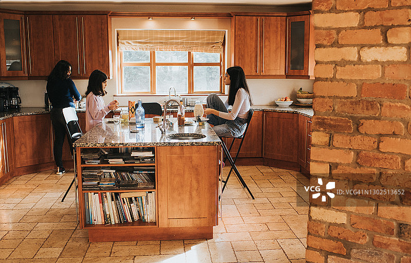 一家人坐在厨房的岛台旁，享用午餐的轻松场景图片素材