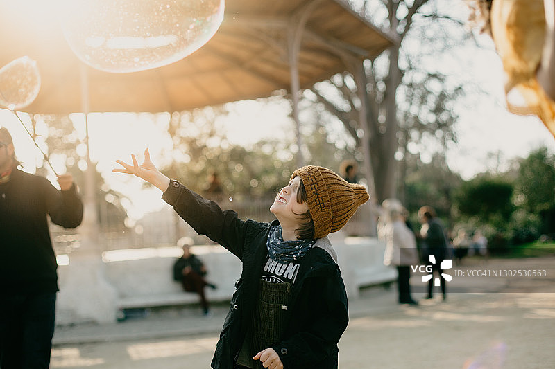日落时分在公园里触摸泡泡的男孩图片素材