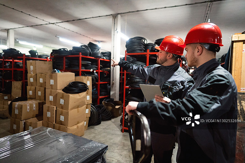 两名仓库工人正在仓库中整理用于健身房的橡胶垫图片素材