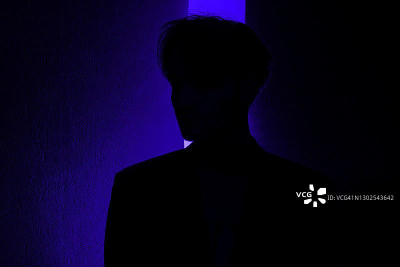 蓝色发光背景中年轻男人的神秘轮廓图片素材