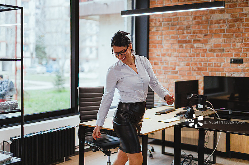 微笑的女商人在带红色砖墙的现代办公室里图片素材