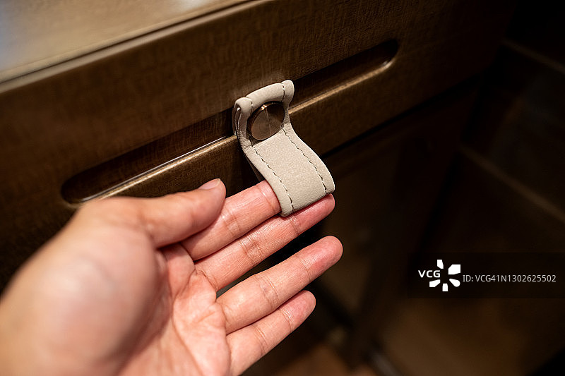 人手拉动抽屉的皮把手图片素材
