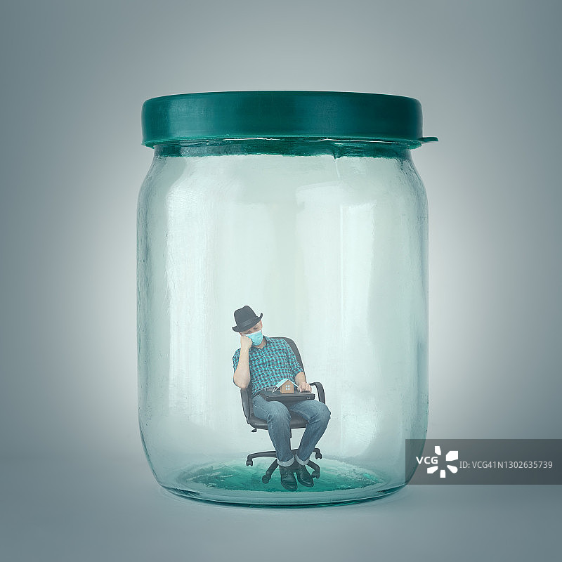 被困在玻璃罐中的男人：新冠疫情隔离概念图片素材