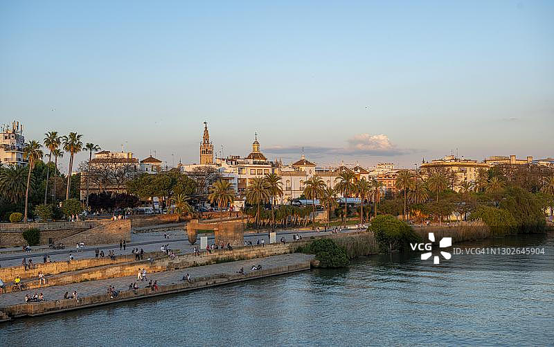 西班牙塞维利亚瓜达尔基维尔河畔盐码头及宽容纪念碑，背景为吉拉尔达钟楼，日落时分图片素材