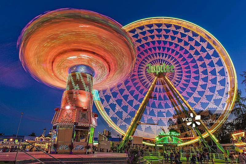 夜间链式旋转木马和摩天轮长时曝光，劳普海姆儿童节，德国巴登-符腾堡州上施瓦本图片素材
