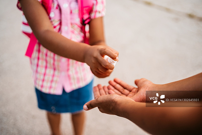 在学校里，女孩和她的妹妹一起使用洗手液图片素材