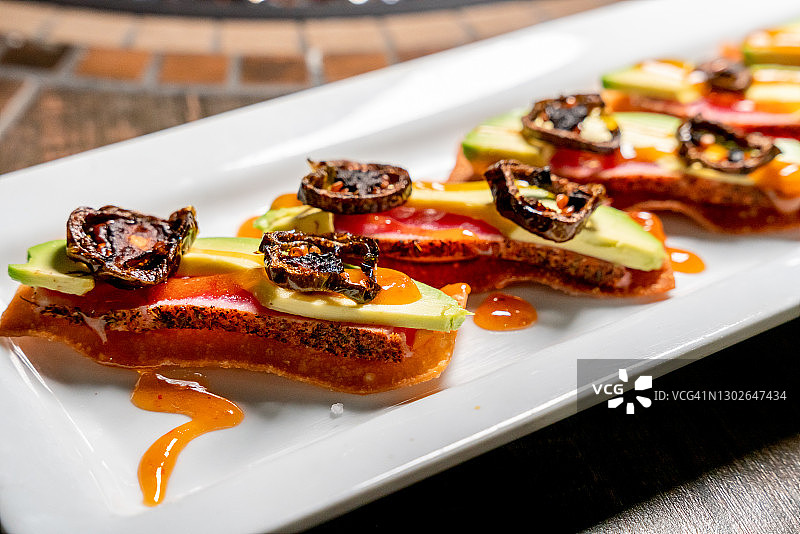 香煎寿司级黄鳍金枪鱼配炸馄饨、牛油果、是拉差奶油奶酪和姜梅酱，佐以炸墨西哥胡椒图片素材