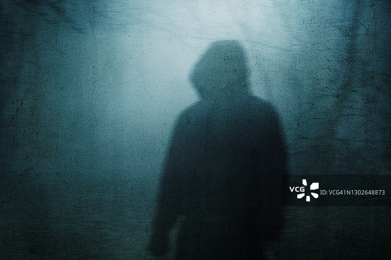 阴沉多雾冬日，诡异森林中戴兜帽人影，抽象恐怖概念图片素材