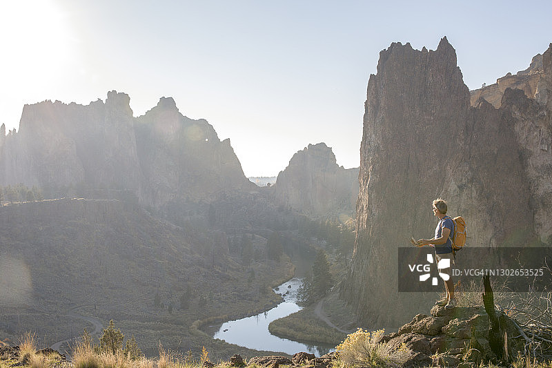 清晨，男人沿着阳光明媚的山脊徒步旅行图片素材