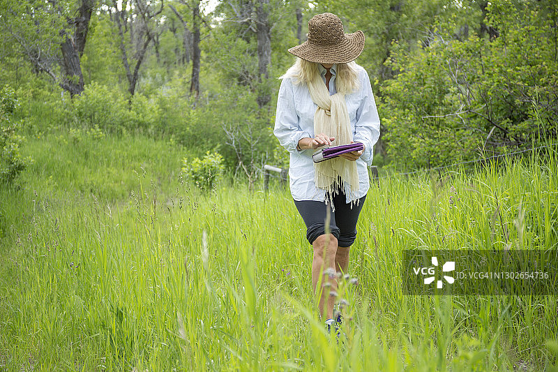 女人走在绿色山地草甸的小路上图片素材