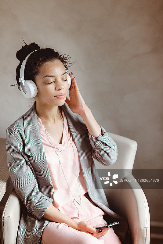 美丽的年轻女子戴着无线耳机听音乐图片素材