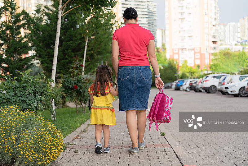 年轻的母亲牵着女儿去上学图片素材