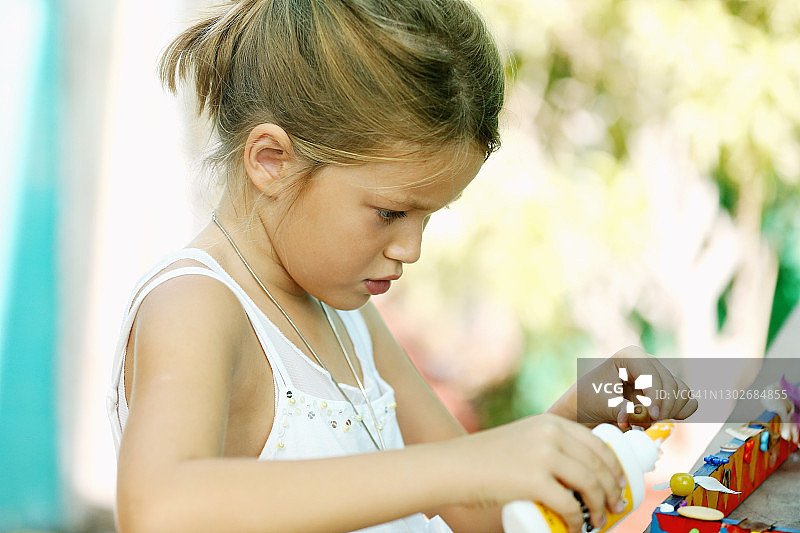 穿着白色连衣裙的女孩在艺术工作室制作手工礼物图片素材