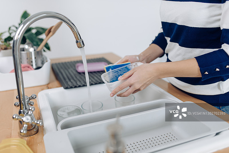 正在清洗塑料餐具的年轻女子图片素材