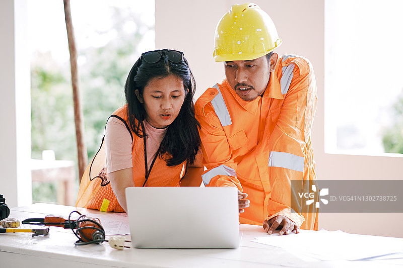 两名亚洲建筑工人在工地使用笔记本电脑工作图片素材