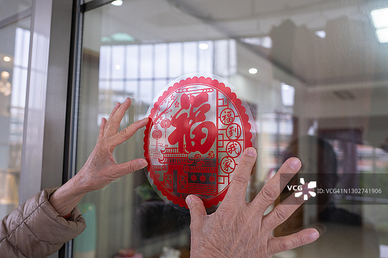 家里的玻璃门上贴着传统的“福”字剪纸，用于中国新年装饰和庆祝图片素材