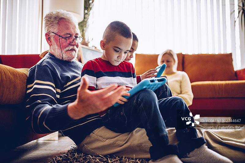 祖父母和孙子孙女在家使用数码平板电脑图片素材