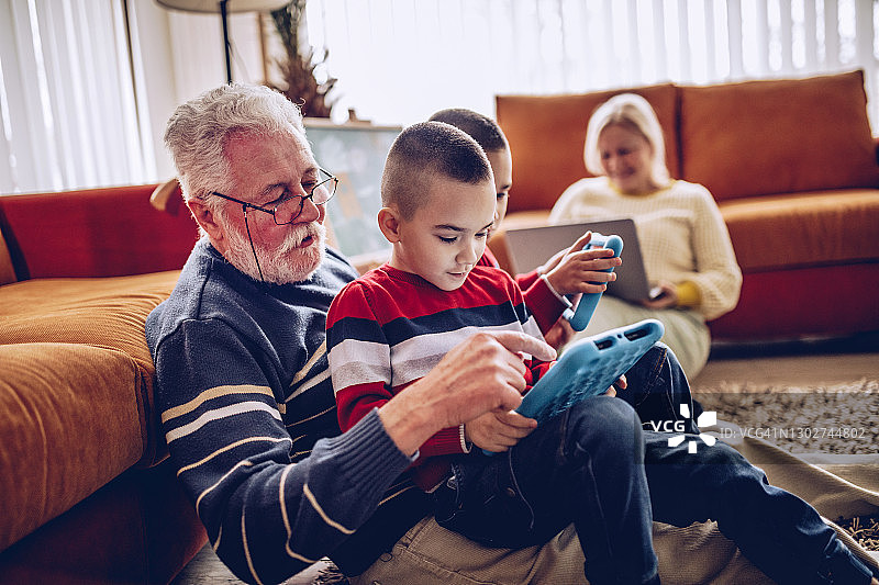 祖父母和孙子孙女在家使用数码平板电脑图片素材