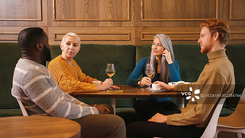 在餐厅里，女士和男人们一边喝酒吃东西一边聊天图片素材