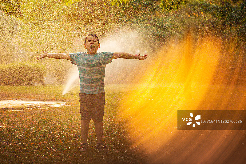 在夕阳下的公园里，一个孩子被巨大的光环笼罩着图片素材