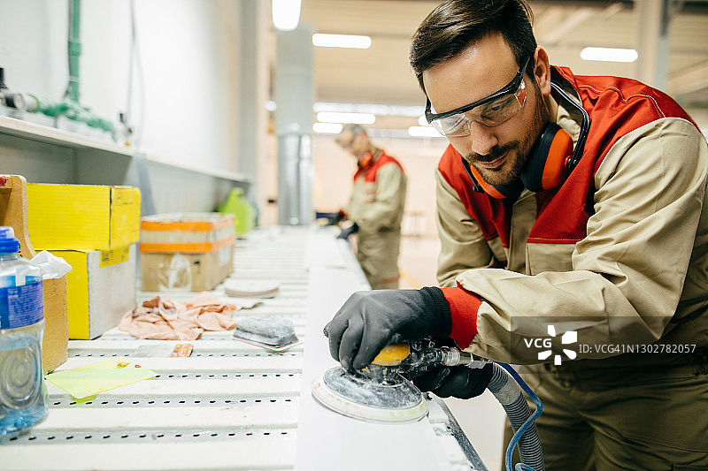 在车间使用砂光机的年轻木匠图片素材