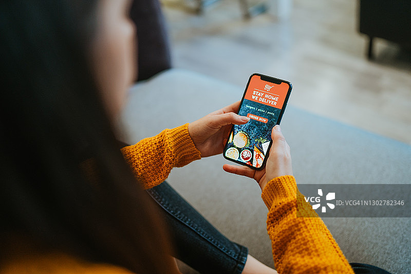 女子在家使用手机App在线订餐图片素材