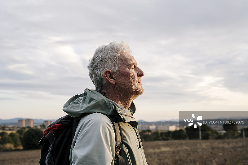 日落时分，年长的男人徒步旅行者在乡村闭着眼睛图片素材