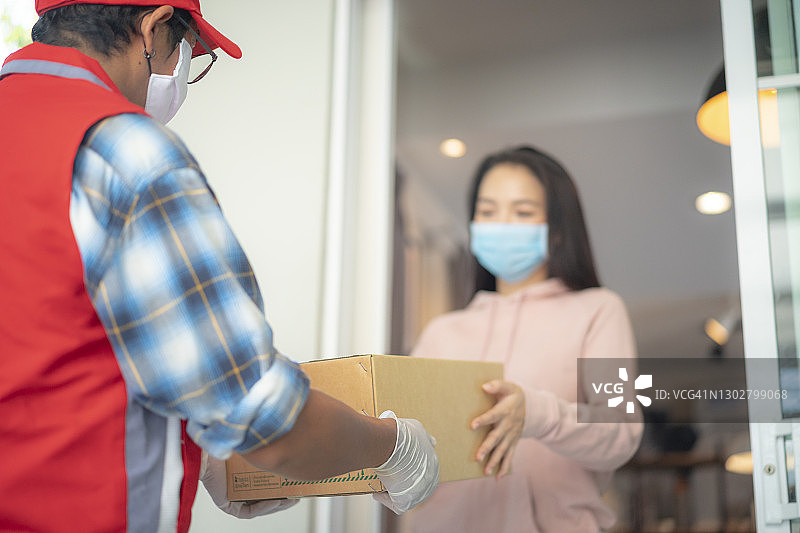 隔离期间送货员戴着手套和口罩送包裹图片素材