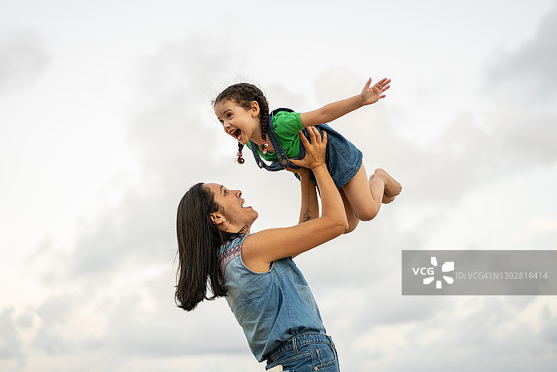 小女孩在母亲的怀里玩飞机图片素材