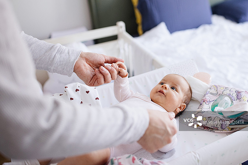 爸爸在婴儿更换垫上和新生女儿玩耍图片素材