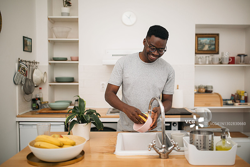 快乐的非裔美国男人在家洗碗图片素材