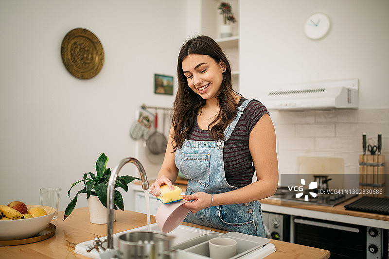 快乐的白人女人在家洗碗图片素材