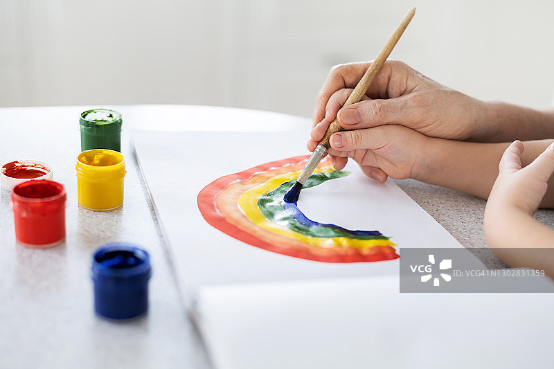 一个孩子的手中在一个成年人的手中学会画彩虹图片素材