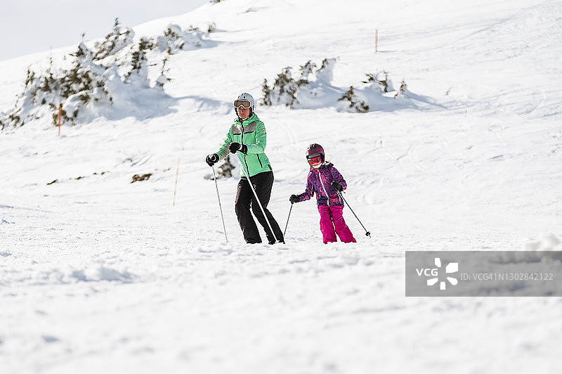 女孩和妈妈在滑雪道上滑雪图片素材
